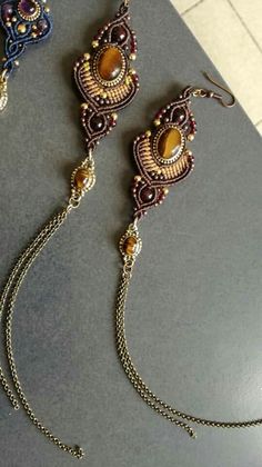 three pieces of jewelry sitting on top of a gray table next to a tile floor