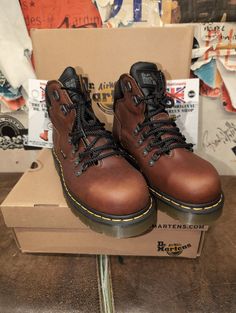 If you need or want a steel toed boot for work or just an everyday all rounder then these fit the bill. A Dr Martens boot that will last many a year due to the quality of both the leather and the sold, thicker, cushioned sole unit. The upper is a Teak Brown waxed leather,strong and extremely good in all weathers. They have a hiking style look with the metal d-rings and padded collar for extra support/ comfort. These boots are Made in Asia, but are of a very good build . They are a UK size 6, Eur Hiking Style, Hiking Fashion, Best Build, Mens Shoes Boots, Dr. Martens Boots, Work Boots, Dr. Martens, Boots Men, Retro Fashion