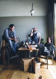 three men sitting at a table in an empty room