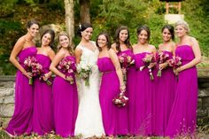 a group of women standing next to each other wearing purple dresses and holding bouquets