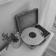 an old record player sitting on top of a table next to a vase with flowers