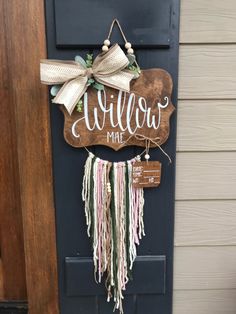 a welcome sign hanging on the side of a door that says willow mae with a bow