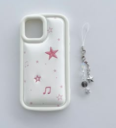 a cell phone case with pink stars and music notes on it next to a pair of earrings