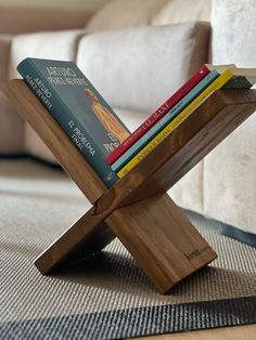 a stack of books sitting on top of a wooden stand in front of a couch