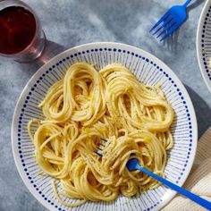 two plates filled with pasta on top of a table next to fork and spoons