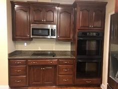 an empty kitchen with wooden cabinets and granite counter tops in the center, along with stainless steel appliances