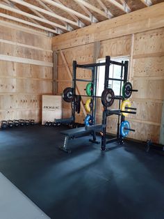 an empty gym room with squat racks and barbells