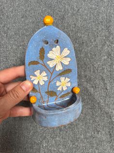 a hand holding a blue and white toilet with flowers painted on it