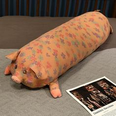 a stuffed pig laying on top of a bed next to a book and magazine cover