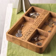 a wooden tray with two compartments filled with different types of cufflinks and coins