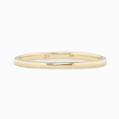 a yellow gold wedding ring with a thin band on a white background, showing the side view