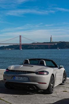 a white porsche roadster parked in front of the golden gate bridge