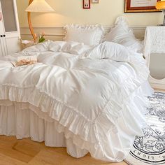 a bed with white ruffled bedspread and pillows