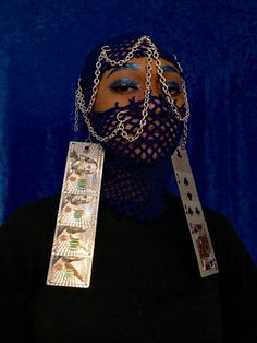 a woman wearing a mask and chain around her neck with playing cards attached to it