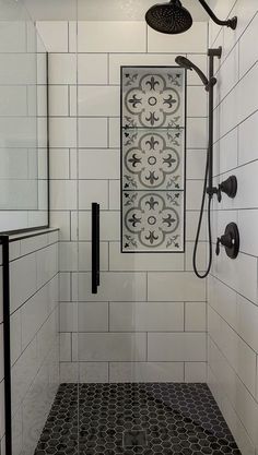 a bathroom with black and white tile on the floor, shower head, and hand held faucet