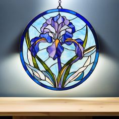 a round stained glass window hanging on the wall above a wooden table with a light fixture