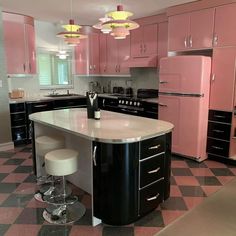 a pink and black kitchen with two stools in the center, an island that has three white stools on it