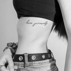 a woman's stomach with the words love yourself tattooed on her lower side ribcage