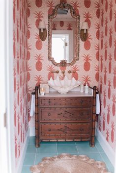 a bathroom with pineapple wallpaper and a mirror above the sink in front of a dresser