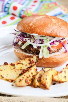 a sandwich and some potato wedges on a white plate with a colorful table cloth