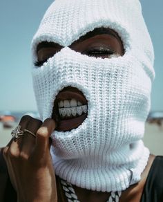 a woman wearing a white mask with braces on her teeth and holding a ring in front of her mouth