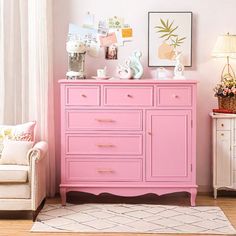 a pink dresser sitting next to a white chair in a room with pictures on the wall