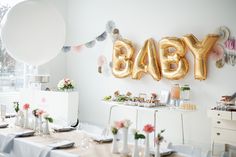 a baby shower is set up with balloons and other decorations on the wall behind it