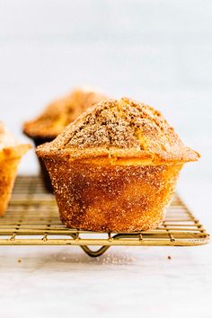 two muffins sitting on a cooling rack with sugar sprinkled on top