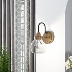 a wall mounted light next to a window with curtains in the background and potted plant