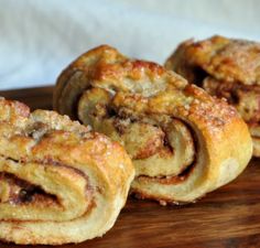 three cinnamon rolls sitting on top of a wooden cutting board