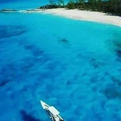 an aerial view of a small boat in the water next to a beach and island