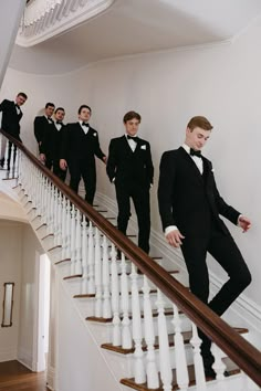 a group of men in tuxedos are standing on the stairs