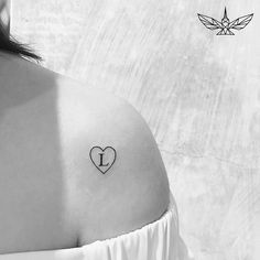 a woman with a small heart tattoo on her upper arm and the letter i behind it