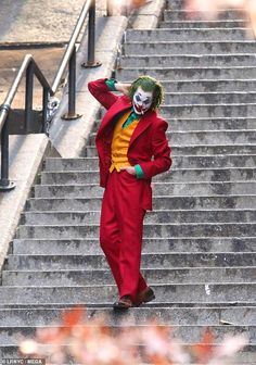 a man dressed as the joker walking down some stairs with his hand on his head