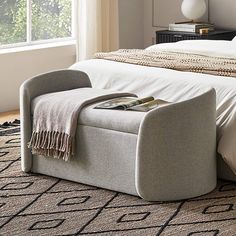 a bedroom with a bed, chair and ottoman on the floor in front of a window