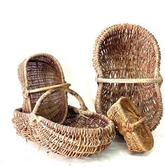 two wicker baskets sitting next to each other on a white surface with one empty basket in the middle