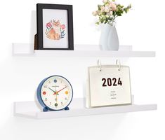 three white shelves with various items on top of them, including a clock and calendar