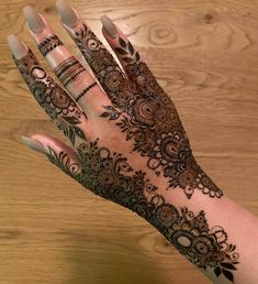 a woman's hand with henna tattoos on it, showing the intricate design