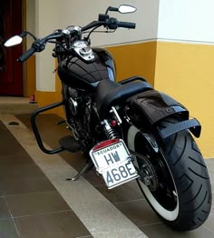 a black motorcycle parked in front of a yellow and white building with a license plate