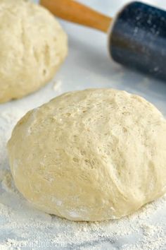 two uncooked doughnuts sitting on top of flour next to a rolling pin