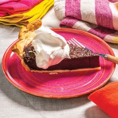 a piece of chocolate pie with whipped cream on top is sitting on a pink plate