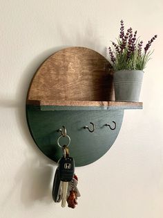 a wooden shelf with two key hooks and a potted plant on the wall next to it