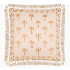 a beige and gold pillow with palm trees on the front, fringe trim around the edges