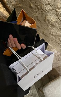 a person holding an open cell phone in their left hand and some boxes on the other