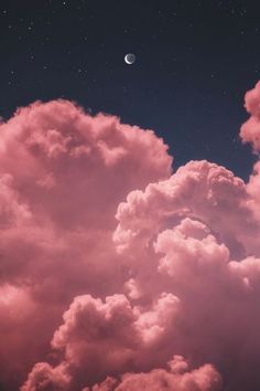 the sky is filled with pink clouds and a half moon in the distance above it