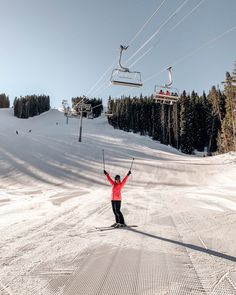 a person on skis is standing in the snow with their arms up and hands raised