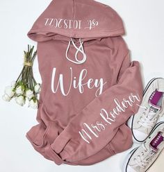 a pink hoodie with the words wheyy on it next to sneakers and flowers