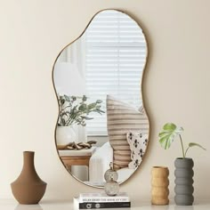 a mirror sitting on top of a table next to vases and a plant in a vase