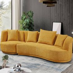 a yellow couch sitting on top of a wooden floor next to a table and potted plant