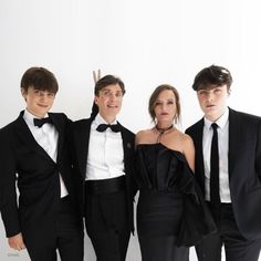 four people in tuxedos posing for a photo